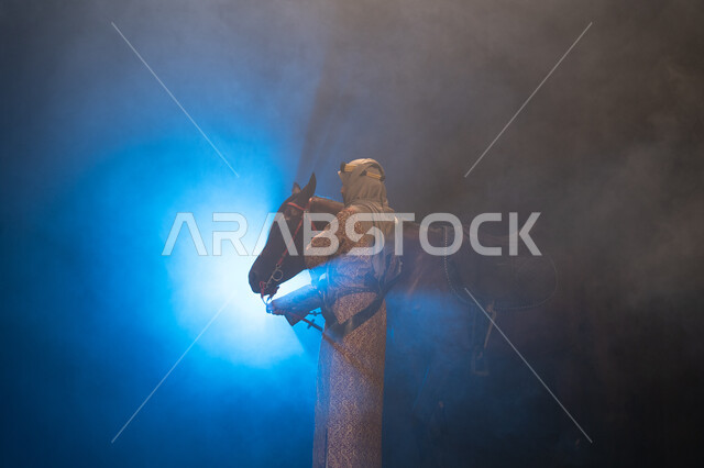 نشر حب الخيل بين أبناء الوطن، ذكرى تأسيس الدولة السعودية الأولى 1727 م، يوم التأسيس السعودي 22 فبراير، ارتداء أزياء المناسبات والأعياد الوطنية، صورة جانبية لرجل خليجي يرتدي الدقلة والغترة يداعب خيله العربي الأصيل، خلفية ضبابية مع إضاءة زرقاء. 