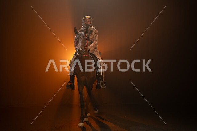 الاحتفال مع الخيل بذكرى تأسيس الدولة السعودية الأولى 1727 م، يوم التأسيس السعودي 22 فبراير، ممارسة هواية ركوب الأحصنة، ارتداء أزياء المناسبات والأعياد الوطنية، رجل خليجي يرتدي الدقلة والغترة يمتطي فرسه البني العربي الأصيل، خلفية ضبابية مع إضاءة صفراء. 