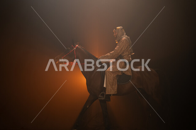  ذكرى تأسيس الدولة السعودية الأولى 1727 م، يوم التأسيس السعودي 22 فبراير، ممارسة هواية ركوب الأحصنة، ارتداء أزياء المناسبات والأعياد الوطنية، صورة جانبية لرجل خليجي يرتدي الدقلة والغترة يمتطي فرسه البني العربي الأصيل، خلفية ضبابية مع إضاءة صفراء. 