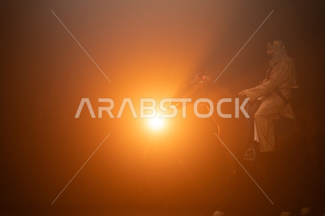 ممارسة هواية ركوب الأحصنة، ارتداء أزياء المناسبات والأعياد الوطنية، ذكرى تأسيس الدولة السعودية الأولى 1727 م، يوم التأسيس السعودي 22 فبراير، صورة جانبية لرجل خليجي يرتدي الدقلة والغترة يمتطي فرسه البني العربي الأصيل، خلفية ضبابية مع إضاءة صفراء. 