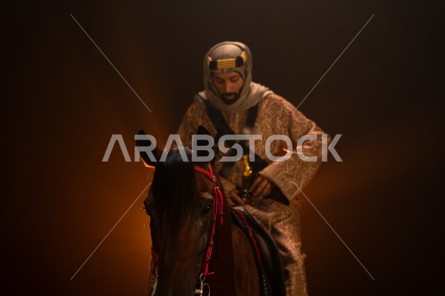 خلفية ضبابية مع إضاءة صفراء، الاحتفال مع الخيل بذكرى تأسيس الدولة السعودية الأولى 1727 م، يوم التأسيس السعودي 22 فبراير، ارتداء أزياء المناسبات والأعياد الوطنية، صورة مقربة لرجل عربي خليجي سعودي يرتدي الدقلة والغترة يمتطي فرسه البني العربي الأصيل. 