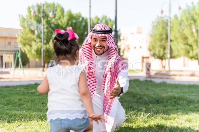 A beautiful girl with Down syndrome spends her time outing with her father in the park, a Saudi Gulf father plays with his daughter outdoors, people of determination, people with special needs