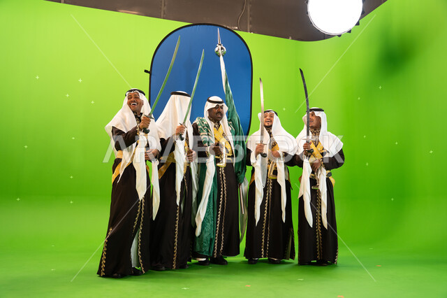 The Najdi Ardha band, songs, and folk dance, the founding of the first Saudi state in 1727 AD, wearing the popular Dhaqla and Ghutra, Saudi traditional folklore arts and performances, celebrating the Saudi Flag Day, March 11, full-length body portrait, gr