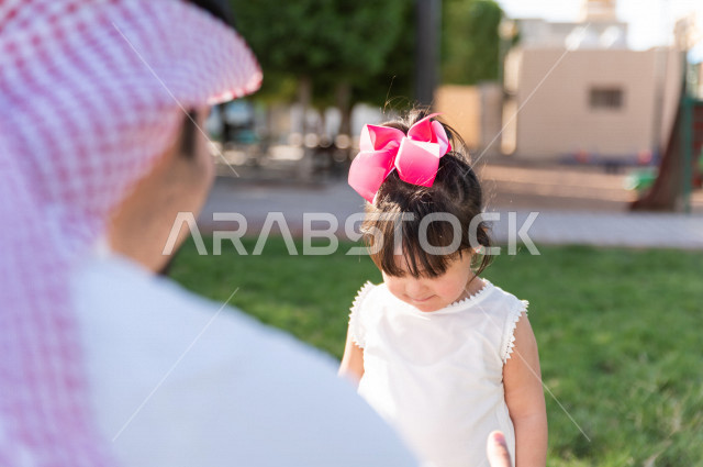 فتاه جميلة مصابة بملازمة داون تقضي وقتها في نزهه مع والدها بالمنتزه ، اب سعودي خليجي يلعب مع ابنته في الهواء الطلق ، أصحاب الهمم ، ذوي الاحتياجات الخاصة