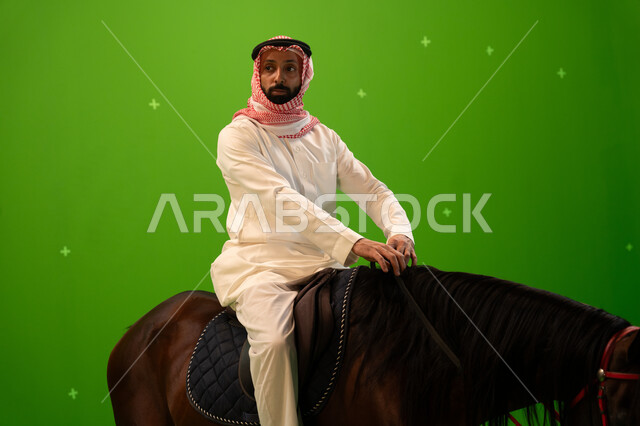 شغف الفروسية وممارسة هواية ركوب الخيل، اتباع تقاليد الاجداد برعاية وتربية الجياد والاهتمام بها، بورتريه مقرب لرجل عربي خليجي سعودي يرتدي الثوب التقليدي والشماغ يمتطي خيل بني عربي أصيل، حب وعشق الاحصنة، خلفية خضراء، كروما