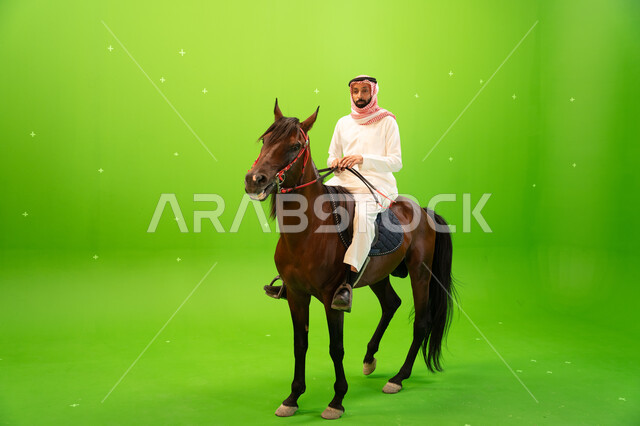 ممارسة هواية ركوب الخيل وشغف الفروسية، بورتريه لرجل عربي خليجي سعودي يرتدي الثوب التقليدي والشماغ يمتطي خيل بني عربي أصيل، حب وعشق الاحصنة، اتباع تقاليد الاجداد برعاية وتربية الجياد والاهتمام بها، خلفية خضراء، كروما
