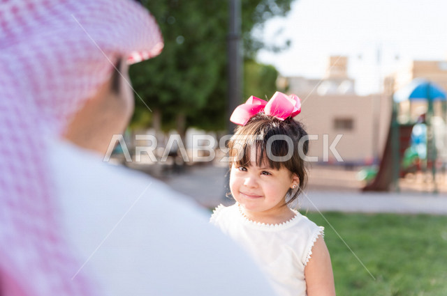 فتاه جميلة مصابة بملازمة داون تقضي وقتها في نزهه مع والدها بالمنتزه ، اب سعودي خليجي يلعب مع ابنته في الهواء الطلق ، أصحاب الهمم ، ذوي الاحتياجات الخاصة