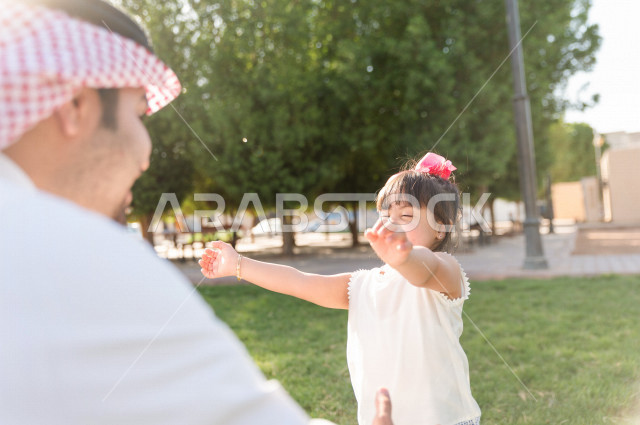 فتاه جميلة مصابة بملازمة داون تقضي وقتها في نزهه مع والدها بالمنتزه ، اب سعودي خليجي يلعب مع ابنته في الهواء الطلق ، أصحاب الهمم ، ذوي الاحتياجات الخاصة