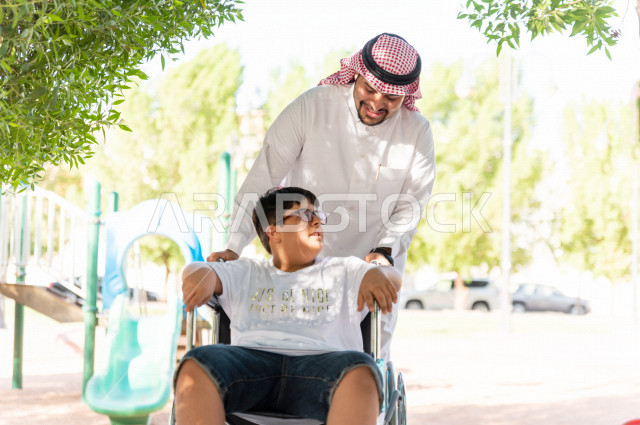 ولد جميل سعوي خليجي مصاب بملازمة داون يقضي وقته في نزهه مع والده  بالمنتزه ، طفل مقعد على كرسي متحرك يستمتع بالهواء الطلق ، أصحاب الهمم ، ذوي الاحتياجات الخاصة ، اعاقة حركية