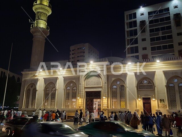 المصلين المسلمين في الساحات الخارجية لجامع المحمل، حركة مرور السيارات على الطرق والشوارع في مدينة جدة، مسجد المحمل المضيء ليلا، الفن الهندسي المعماري لمساجد السعودية، معالم جدة القديمة في البلد التاريخي