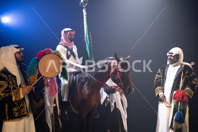 عروض فرقة الفلكلور التراثي في يوم العلم 11 مارس, الاحتفال مع الأحصنة في اليوم الوطني في 23 سبتمبر في وضح الليل, نشر حب الخيل بين أبناء الوطن, رجل يمتطي خيل عربي بني أصيل, حب الفروسية وشغف الاهتمام بها, الأعياد والمناسبات الوطنية, ارتداء زي العرضة النجدية.