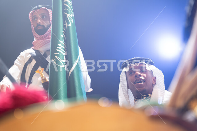 النظر إلى شيء ما، الاحتفالات والمناسبات الوطنية, صورة مقربة لرجل عربي خليجي يرتدي الزي السعودي يحتفل باليوم الوطني 23 سبتمبر في وقت الليل,  ذكرى يوم العلم السعودي 11 مارس، خلفية سوداء مع إضاءة بيضاء.