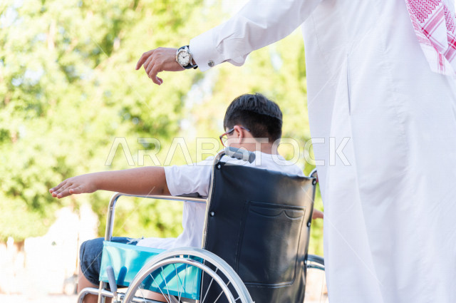 ولد جميل سعوي خليجي مصاب بملازمة داون يقضي وقته في نزهه مع والده  بالمنتزه ، طفل مقعد على كرسي متحرك يستمتع بالهواء الطلق ، أصحاب الهمم ، ذوي الاحتياجات الخاصة ، اعاقة حركية