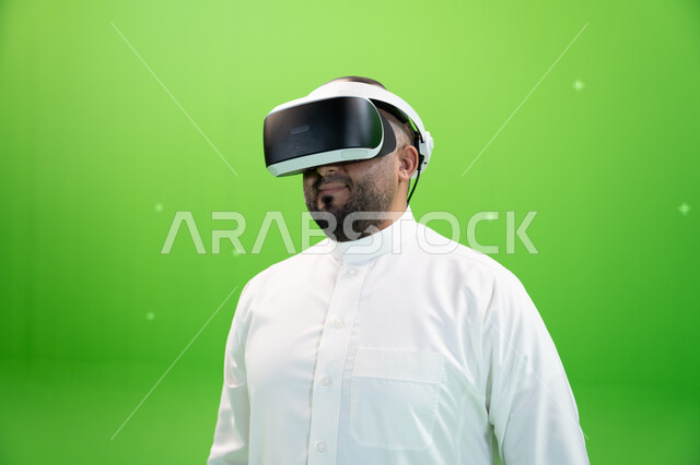 Entertainment and leisure time, using advanced modern technologies in watching movies and simulating the imaginary world, a close-up portrait of a Saudi Gulf Arab man wearing traditional clothing, wearing 3D virtual reality glasses, green background, chro