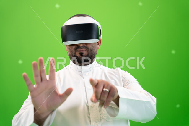 ايماءات تدل على دفع عنصر هولوجرامي، بورتريه مقرب لرجل عربي خليجي سعودي يرتدي الزي التقليدي يلبس نظارة الواقع الإفتراضي ثلاثية الأبعاد يرفع اصبع السبابة للنقر على شاشه هولوجراميه، خلفية خضراء، كروما