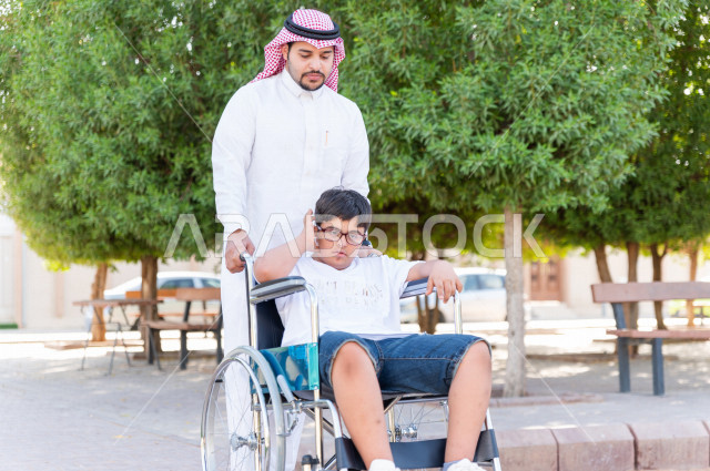 ولد جميل سعوي خليجي مصاب بملازمة داون يقضي وقته في نزهه مع والده  بالمنتزه ، طفل مقعد على كرسي متحرك يستمتع بالهواء الطلق ، أصحاب الهمم ، ذوي الاحتياجات الخاصة ، اعاقة حركية