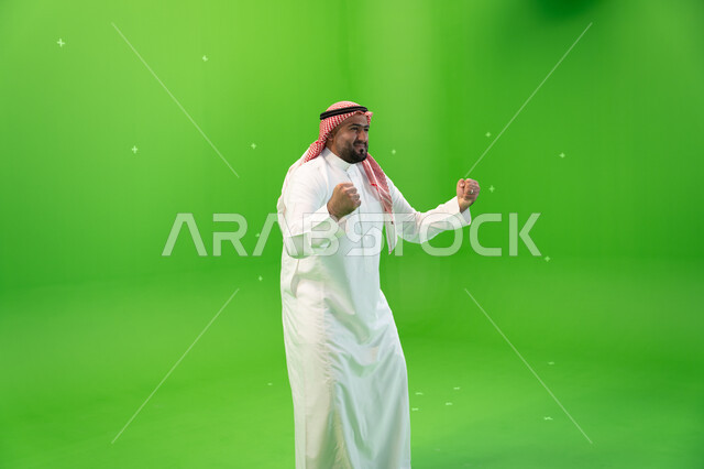 Admiration, contentment and happiness, achieving goals and accomplishing tasks, a portrait of a Saudi Arabian Gulf man wearing the traditional thobe and shemagh and raising his hands in joy in victory, gestures indicating victory and gain, a sign of joy a