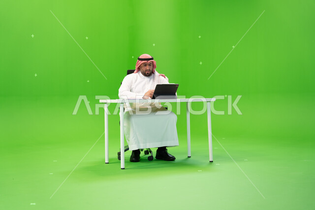 القيام بمحادثات الفيديو عبر الانترنت, إجراء مقابلات عمل أونلاين, استخدام الأجهزة والتقنيات الحديثة, بورتريه لموظف عربي سعودي خليجي يرتدي الزي التقليدي السعودي يقوم بالعمل داخل مكتبه, مهن ووظائف سعوديةالاجتهاد في تطوير خطة العمل, خلفية خضراء, كروما. 