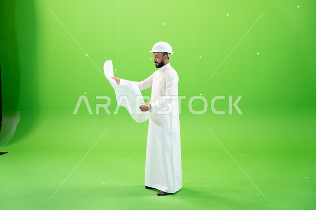 التدقيق في مخطط الانشاءات, الحرف والمهن السعودية, إدارة المهام والمشاريع الهندسية, بورتريه لمهندس عربي خليجي سعودي يرتدي الثوب التقليدي وخوذة الحماية في موقع العمل, صورة الجسم بالطول الكامل, خلفية خضراء, كروما
