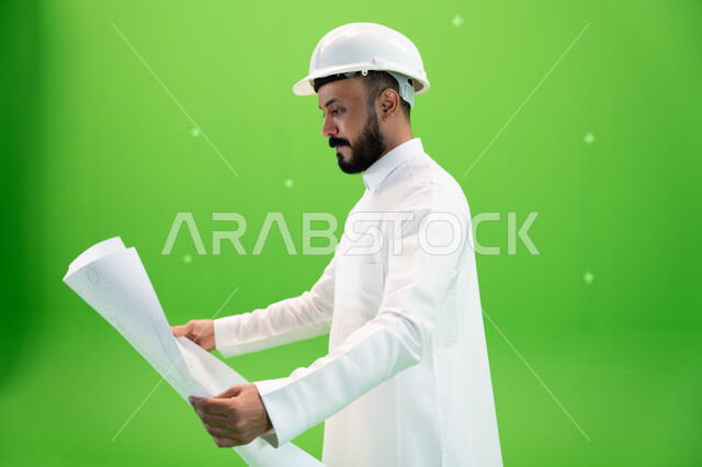 تطوير وتنمية المجال الهندسي السعودي, النظر إلى مخطط الإنشاءات, بورتريه من الجانب لمهندس عربي خليجي سعودي يرتدي الثوب التقليدي وقبعة الحماية في موقع العمل, مفهوم الهندسة وأعمال البناء, مهن ووظائف سعودية, متابعة الأعمال الهندسية, خلفية خضراء, كروما