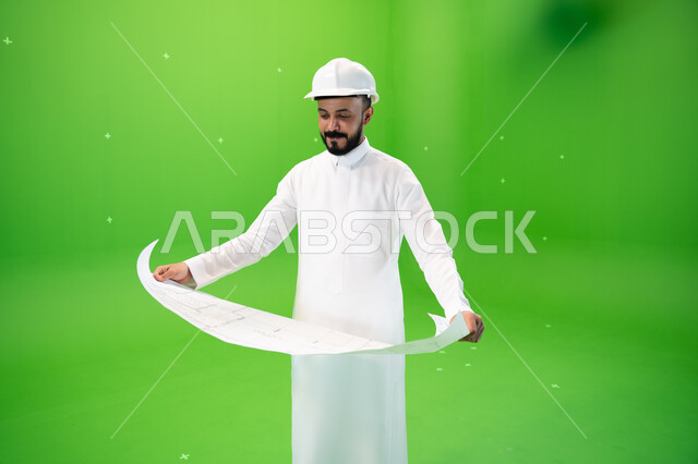 مفهوم الهندسة وأعمال البناء, النظر إلى مخطط الإنشاءات, بورتريه لمهندس عربي خليجي سعودي يرتدي الثوب التقليدي وقبعة الحماية في موقع العمل, مهن ووظائف سعودية,  تنمية وتطوير المجال الهندسي السعودي, متابعة الأعمال الهندسية, خلفية خضراء, كروما