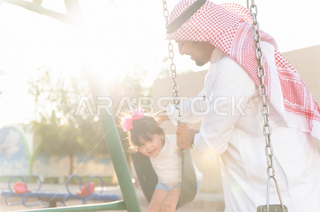 فتاه جميلة مصابة بملازمة داون تقضي وقتها في نزهه مع والدها بالمنتزه ، اب سعودي خليجي يأرجح ابنته على  لعبة الارجوحة ، أصحاب الهمم ، ذوي الاحتياجات الخاصة