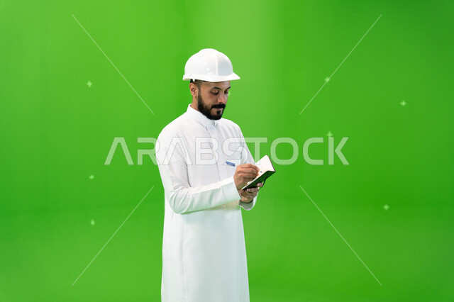 الإعمار بسواعد أبناء الوطن, مهن ووظائف سعودية, العمل في القطاع الهندسي السعودي, بورتريه لمهندس عربي خليجي سعودي يرتدي قبعة الحماية يقف في موقع العمل, تسجيل وتدوين ملاحظات البناء والإنشاءات, خلفية خضراء, كروما