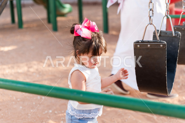 فتاه جميلة مصابة بملازمة داون تقضي وقتها في نزهه مع والدها بالمنتزه ، اب سعودي خليجي يأرجح ابنته على  لعبة الارجوحة ، أصحاب الهمم ، ذوي الاحتياجات الخاصة