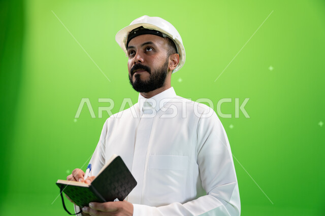 النظر إلى شيء ما, مهن ووظائف سعودية, العمل في القطاع الهندسي السعودي, بورتريه مقرب لمهندس عربي خليجي سعودي يرتدي قبعة الحماية يقف في موقع العمل, تسجيل وتدوين ملاحظات البناء والإنشاءات, الإعمار بسواعد أبناء الوطن, خلفية خضراء, كروما