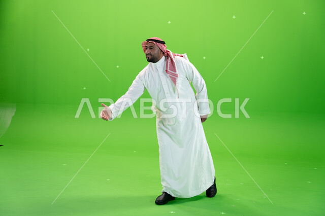 اشارات يدين تدل على الترحيب بالضيوف والاستقبال، رجل عربي خليجي سعودي يرتدي الثوب والشماغ التقليدي يمد كفه لإلقاء التحيه والسلام, صورة الجسم بالطول الكامل، خلفية خضراء، كروما