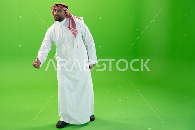 حركات يدين تدل على إلقاء التحيه والسلام، رجل عربي خليجي سعودي يرتدي الثوب والشماغ التقليدي يمد كفه لاستقبال الضيوف و الترحيب بهم ، صورة الجسم بالطول الكامل، خلفية خضراء، كروما