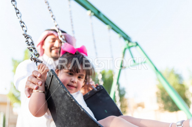 فتاه جميلة مصابة بملازمة داون تقضي وقتها في نزهه مع والدها بالمنتزه ، اب سعودي خليجي يأرجح ابنته على  لعبة الارجوحة ، أصحاب الهمم ، ذوي الاحتياجات الخاصة