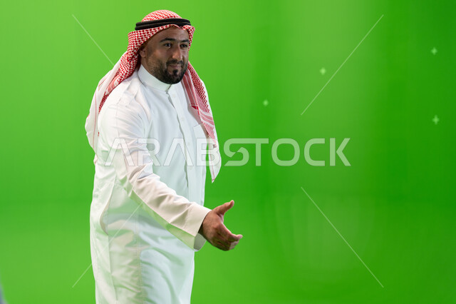 ايماءات يدين تدل على استقبال الضيوف و الترحيب بهم، رجل عربي خليجي سعودي يرتدي الثوب والشماغ التقليدي يمد كفه لإلقاء التحيه والسلام، خلفية خضراء، كروما