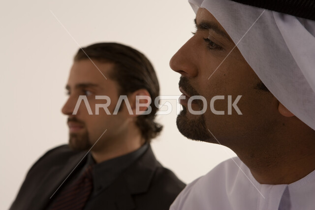 إيماءات التركيز والانتباه، الشراكة والتعاون في انجاز العمل, تأهيل وتدريب رجال الأعمال، مهن ووظائف اماراتية, صورة مقربة لرجل عربي خليجي اماراتي يرتدي الكندورة الاماراتية ورجل بالبدلة الرسمية يجلسان داخل مقر الشركة