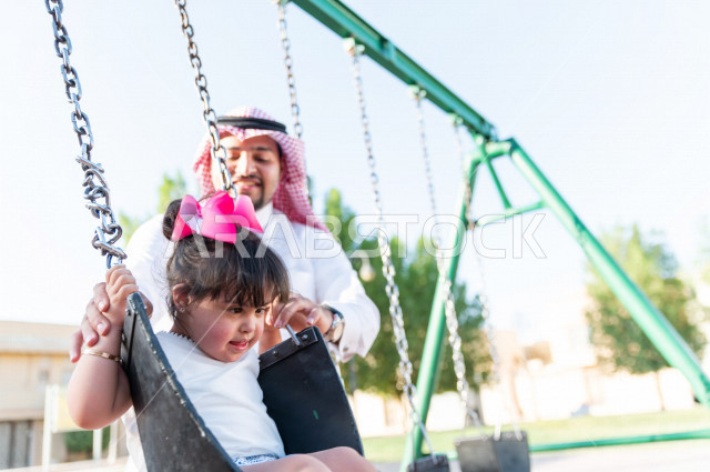 فتاه جميلة مصابة بملازمة داون تقضي وقتها في نزهه مع والدها بالمنتزه ، اب سعودي خليجي يأرجح ابنته على  لعبة الارجوحة ، أصحاب الهمم ، ذوي الاحتياجات الخاصة