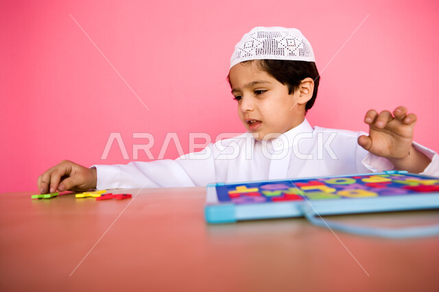Using and recognizing the forms of Arabic letters, learning skill through educational games, a close-up portrait of an Arab Gulf Emirati child wearing Emirati clothes and playing with the alphabet puzzle game, enjoying useful recreational activities, colo