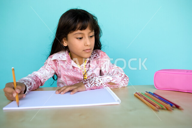 استلهام الرسمات من الأشياء المجاورة, تطوير وتنمية الهوايات, أدوات وقرطاسية التلوين، بورتريه مقرب لفتاة صغيرة عربية خليجية إماراتية تقوم بالرسم والتلوين بالأقلام الخشبية، رعاية المواهب والاهتمام بها في الإمارات العربية المتحدة, خلفية زرقاء