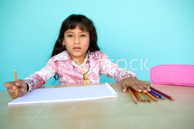 Inspiration for drawings from surrounding things, development and development of hobbies, coloring tools and stationery, close-up portrait of a young Arab Gulf Emirati girl drawing and coloring with wooden pens, nurturing and caring for talents in the Uni