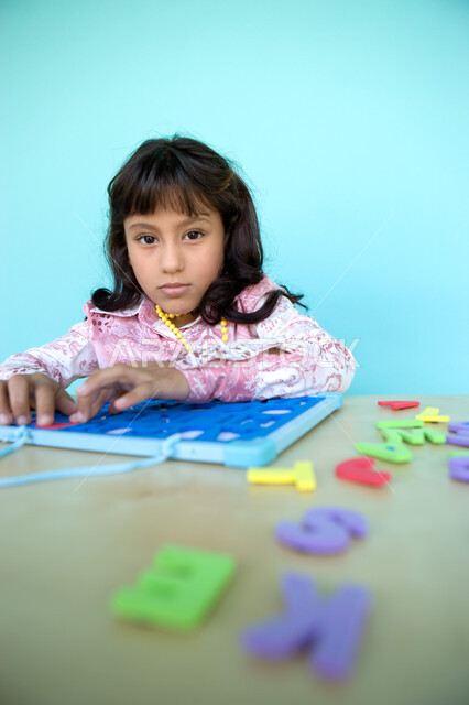 Investing leisure time in useful activities, entertainment and entertainment with educational activities, learning through educational games, recognizing the shapes of foreign letters, a close-up portrait of an Arab Gulf-Emirati girl looking at the camera