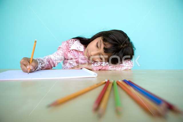 تطوير وتنمية الهوايات, إيماءات الاندماج والتركيز في الأنشطة الفنية، أدوات وقرطاسية التلوين، بورتريه مقرب لفتاة صغيرة عربية خليجية إماراتية تقوم بالرسم والتلوين بالأقلام الخشبية، رعاية المواهب والاهتمام بها في الإمارات العربية المتحدة, خلفية زرقاء