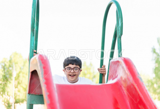 ولد سعوي خليجي مصاب بملازمة داون يقضي وقته في نزهه مع والده  بالمنتزه ، يستمتع باللعاب على الارجوحة ، أصحاب الهمم ، ذوي الاحتياجات الخاصة