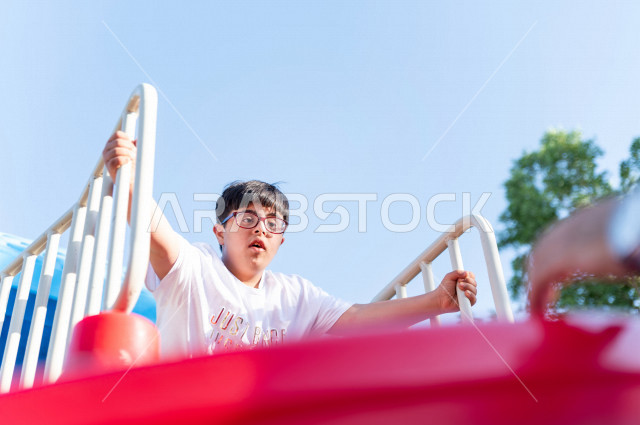 ولد سعوي خليجي مصاب بملازمة داون يقضي وقته في نزهه مع والده  بالمنتزه ، يستمتع باللعاب على الارجوحة ، أصحاب الهمم ، ذوي الاحتياجات الخاصة