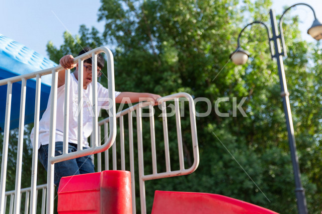 ولد سعوي خليجي مصاب بملازمة داون يقضي وقته في نزهه مع والده  بالمنتزه ، يستمتع باللعاب على الارجوحة ، أصحاب الهمم ، ذوي الاحتياجات الخاصة