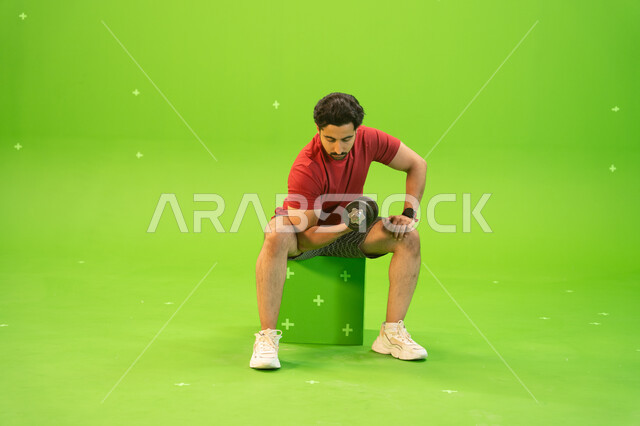 تمارين رفع الأثقال، القوة والتحدي والتحفيز لأسلوب حياة صحي، نشاط بدني للمحافظة على الصحة واللياقة الجسدية، رفع الأوزان الحديدية الثقيلة، تقوية عضلات الجسم وبناؤها، بورتريه لشاب عربي خليجي سعودي يمارس التمارين الرياضية مع الدمبلز، خلفية خضراء، كروما.