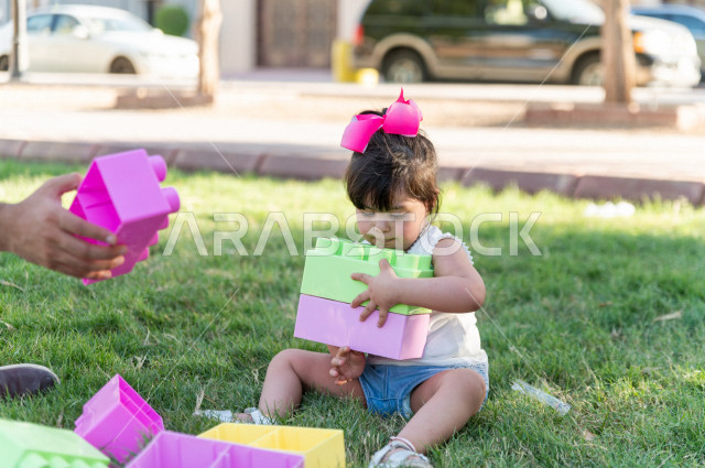 A beautiful girl with Down syndrome spends her time outing with her father in the park, a Saudi Gulf father plays with his daughter outdoors, people of determination, people with special needs