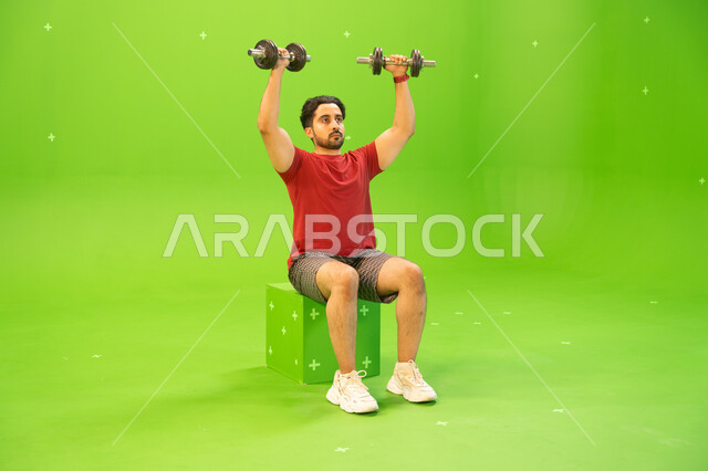 Strengthening and building body muscles, weight lifting exercises, strength, challenge and motivation for a healthy lifestyle, a portrait of a Saudi Gulf Arab young man exercising with dumbbells, physical activity to maintain health and physical fitness, 