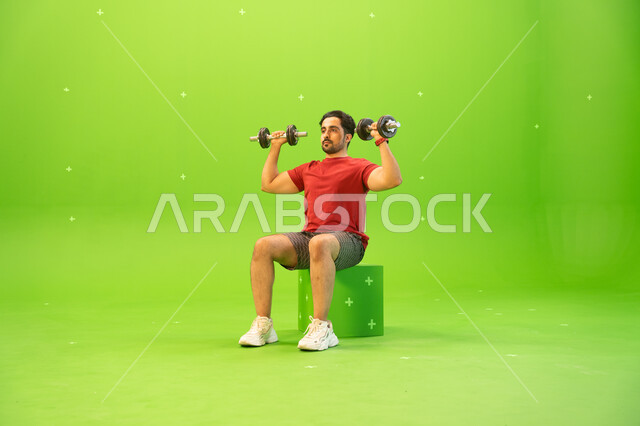 Strengthening and building body muscles, weight lifting exercises, strength, challenge and motivation for a healthy lifestyle, a portrait of a Saudi Gulf Arab young man exercising with dumbbells, physical activity to maintain health and physical fitness, 