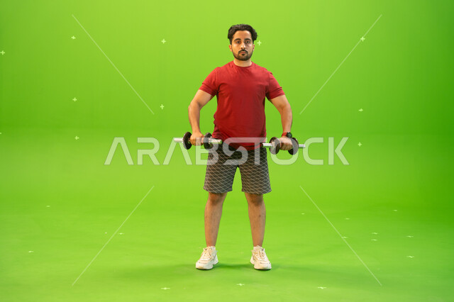 كمال الأجسام وتقوية وبناء العضلات، تمارين رفع الأثقال، أسلوب حياة صحي، بورتريه لشاب عربي خليجي سعودي يمارس التمارين الرياضية مع الدمبلز، نشاط بدني للمحافظة على الصحة واللياقة الجسدية، رفع الأوزان الحديدية الثقيلة، خلفية خضراء، كروما.