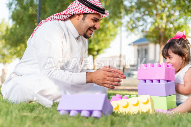 فتاه جميلة مصابة بملازمة داون تقضي وقتها في نزهه مع والدها بالمنتزه ، اب سعودي خليجي يلعب مع ابنته في الهواء الطلق ، أصحاب الهمم ، ذوي الاحتياجات الخاصة