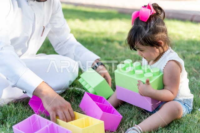A beautiful girl with Down syndrome spends her time outing with her father in the park, a Saudi Gulf father plays with his daughter outdoors, people of determination, people with special needs